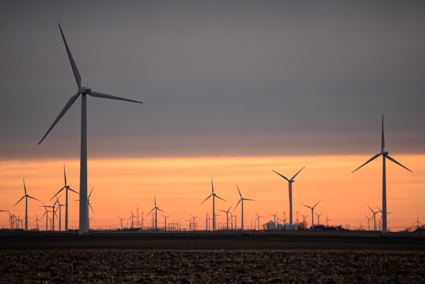 Wind turbines on a brown field at sunset