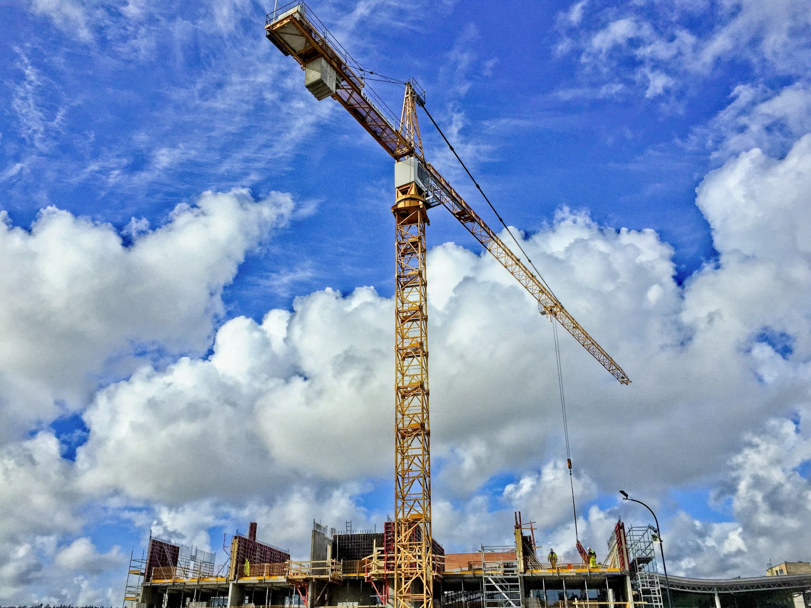 A yellow tower crane against a blue sky